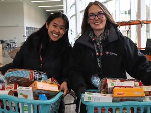  Lake Michigan College employees Anna Bockheim, left, and Laura Henderson-Whiteford carry holiday food baskets prepared for community members in December 2022. 
