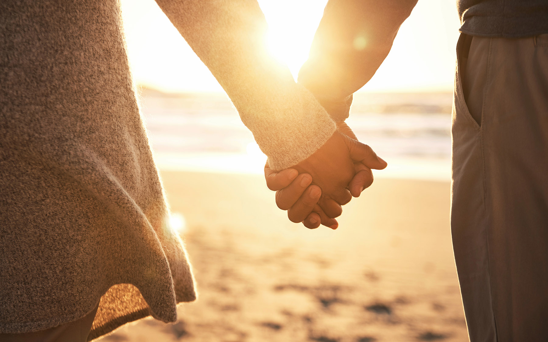 Couple holding hands at the beach at sunset