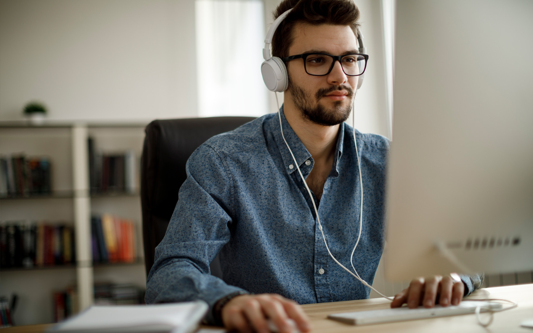 Person in headphones working on a large monitor.