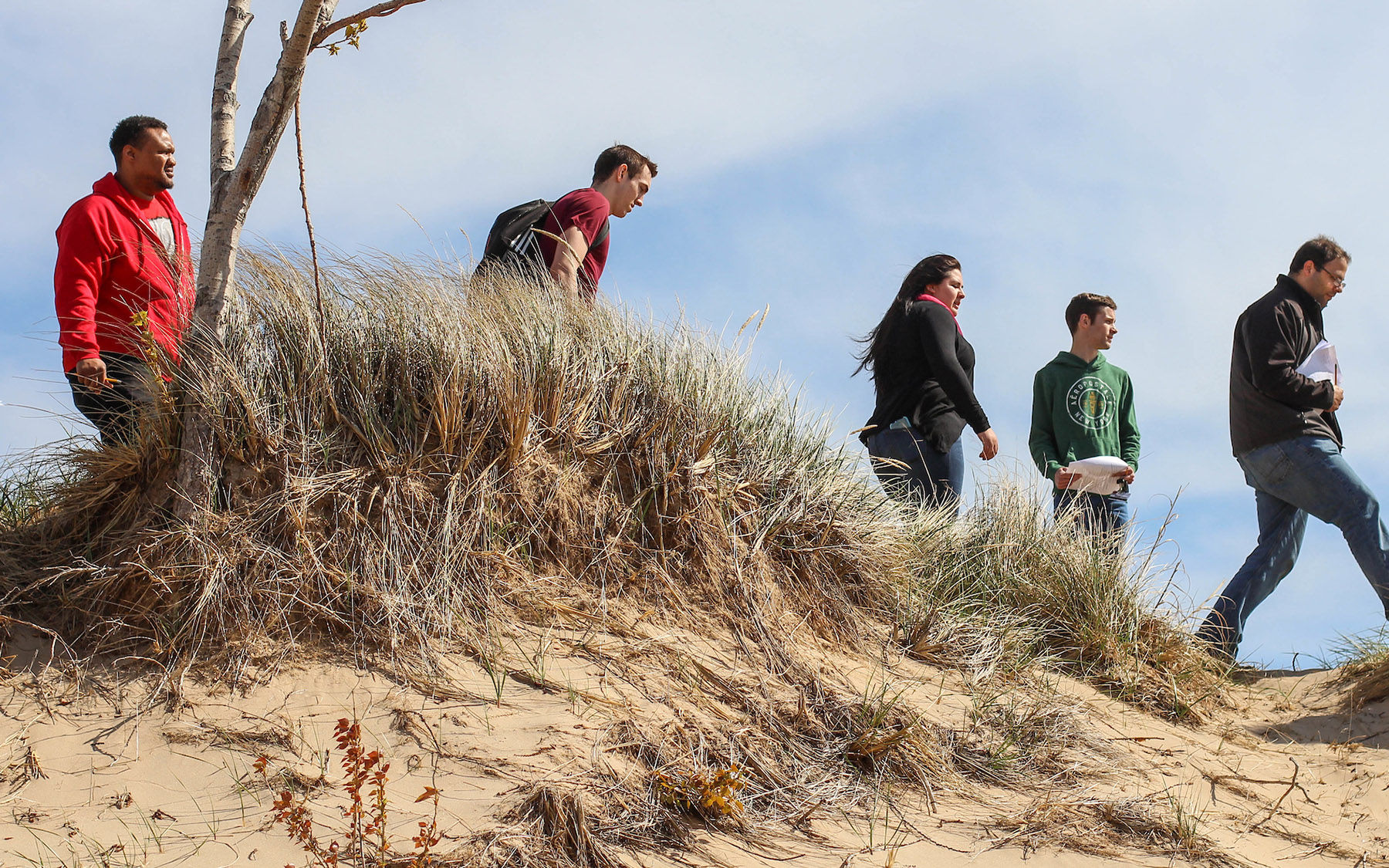 Students walking across a sand dune in fall.