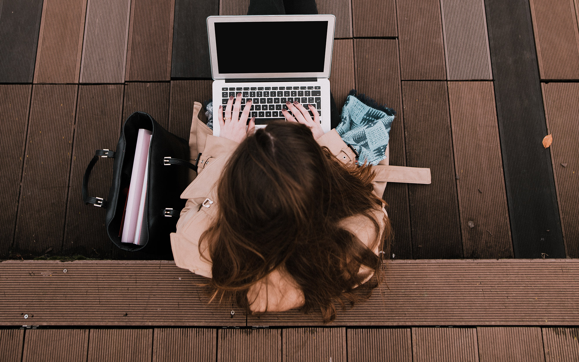 Overhead view of a student working on a laptop outside.