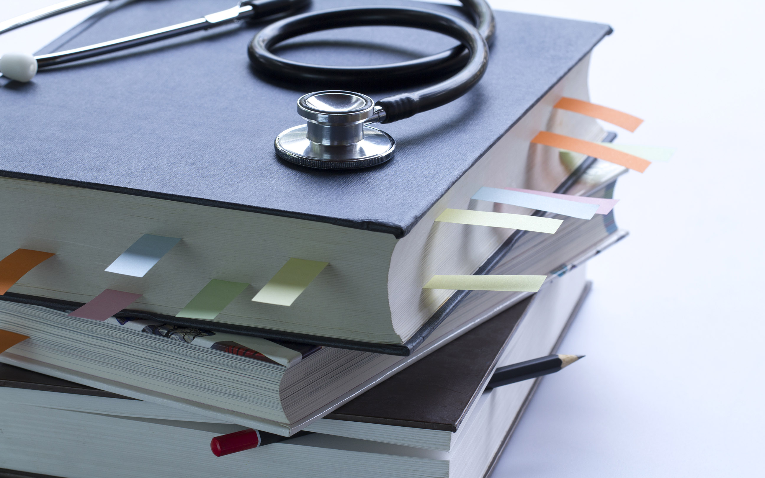 Stethoscope, pencil and a book on a table.