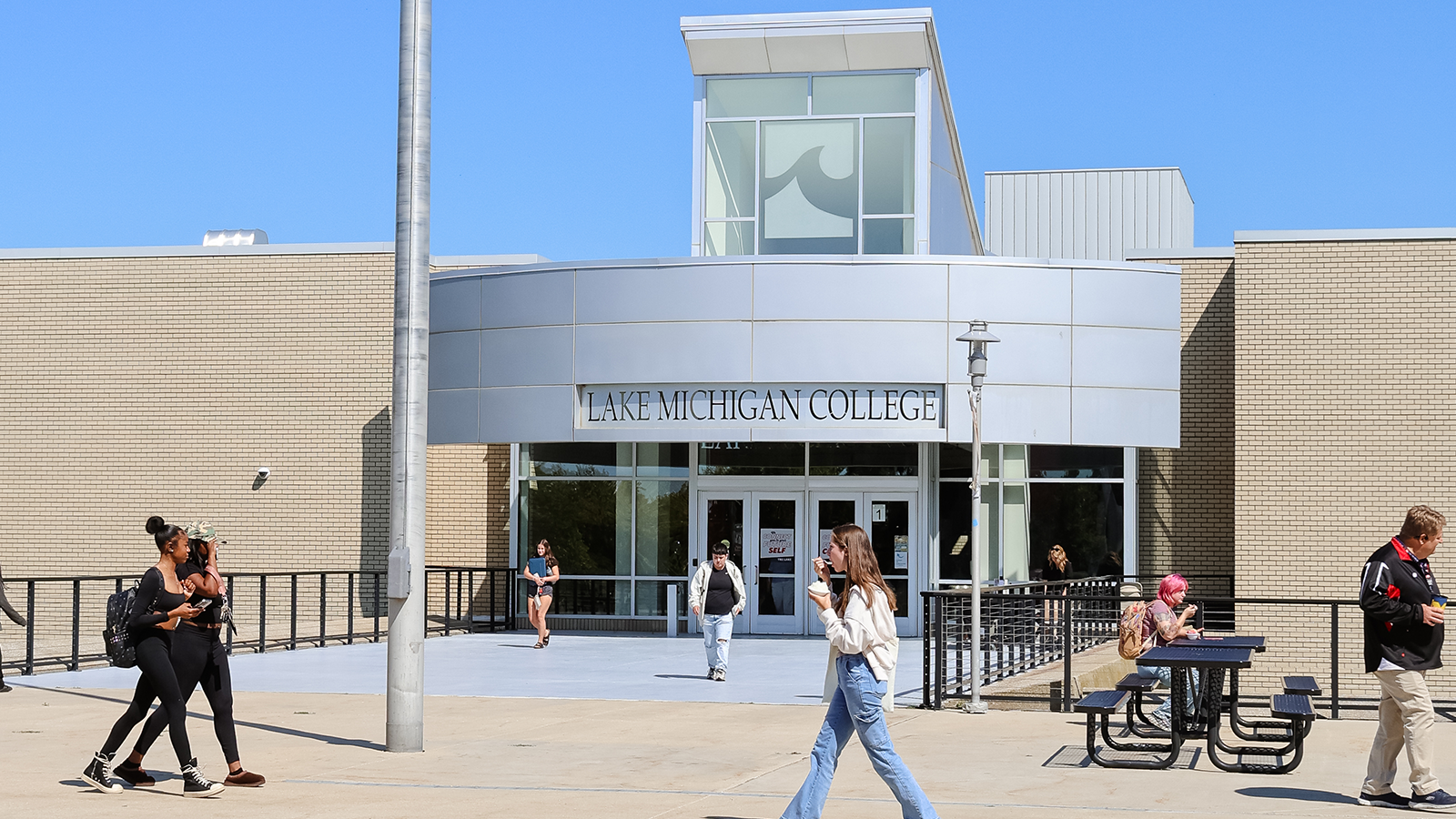 Students and faculty walking in broad daylight in front of Lake Michigan College