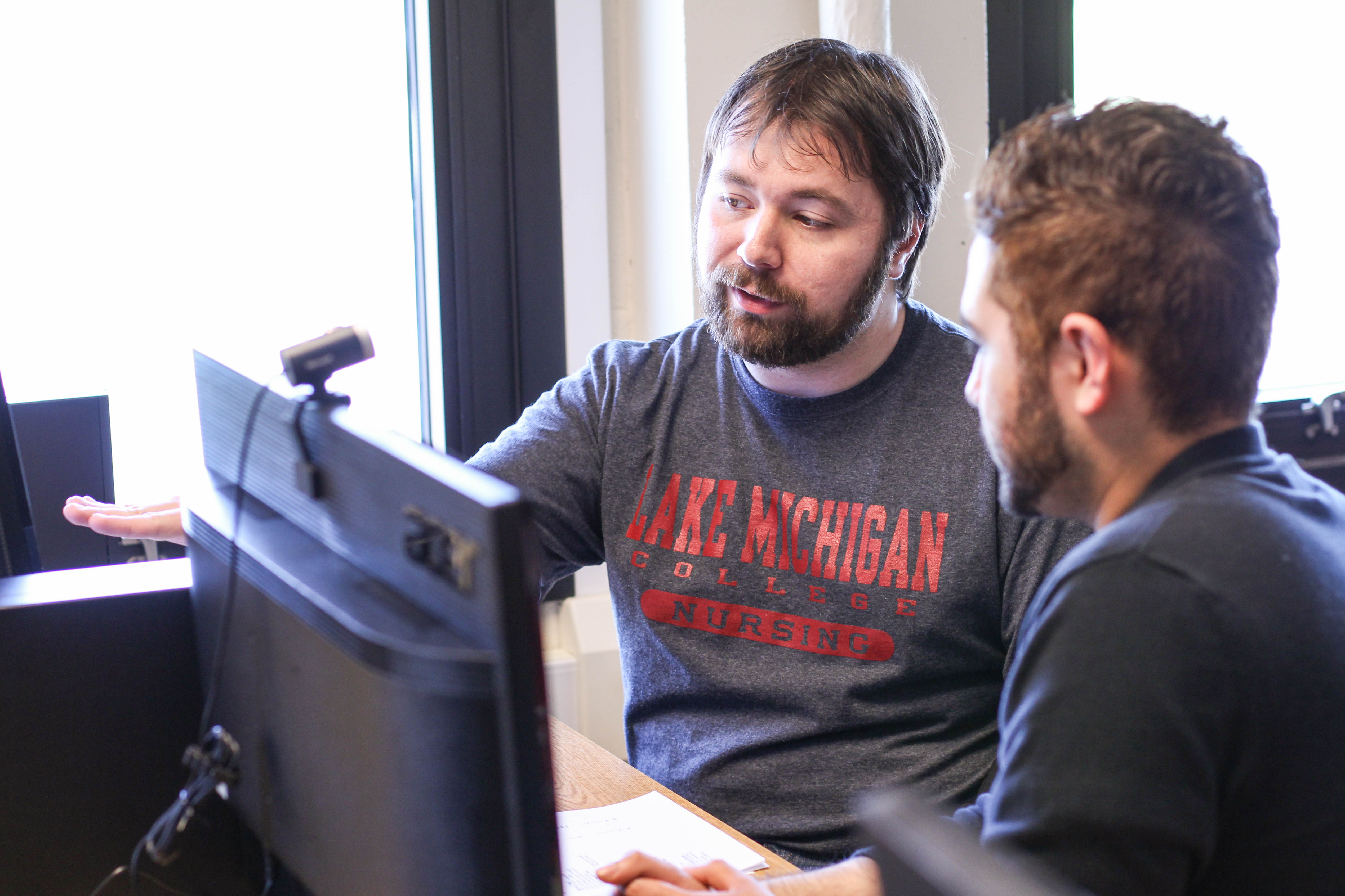 Two men looking at a computer screen together.