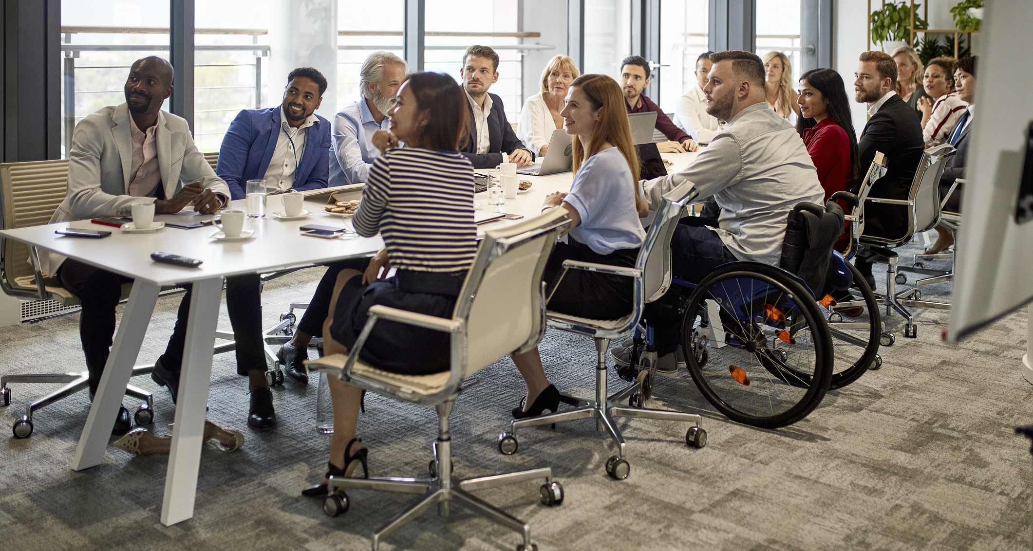 A team of people at a conference room table watching a presentation