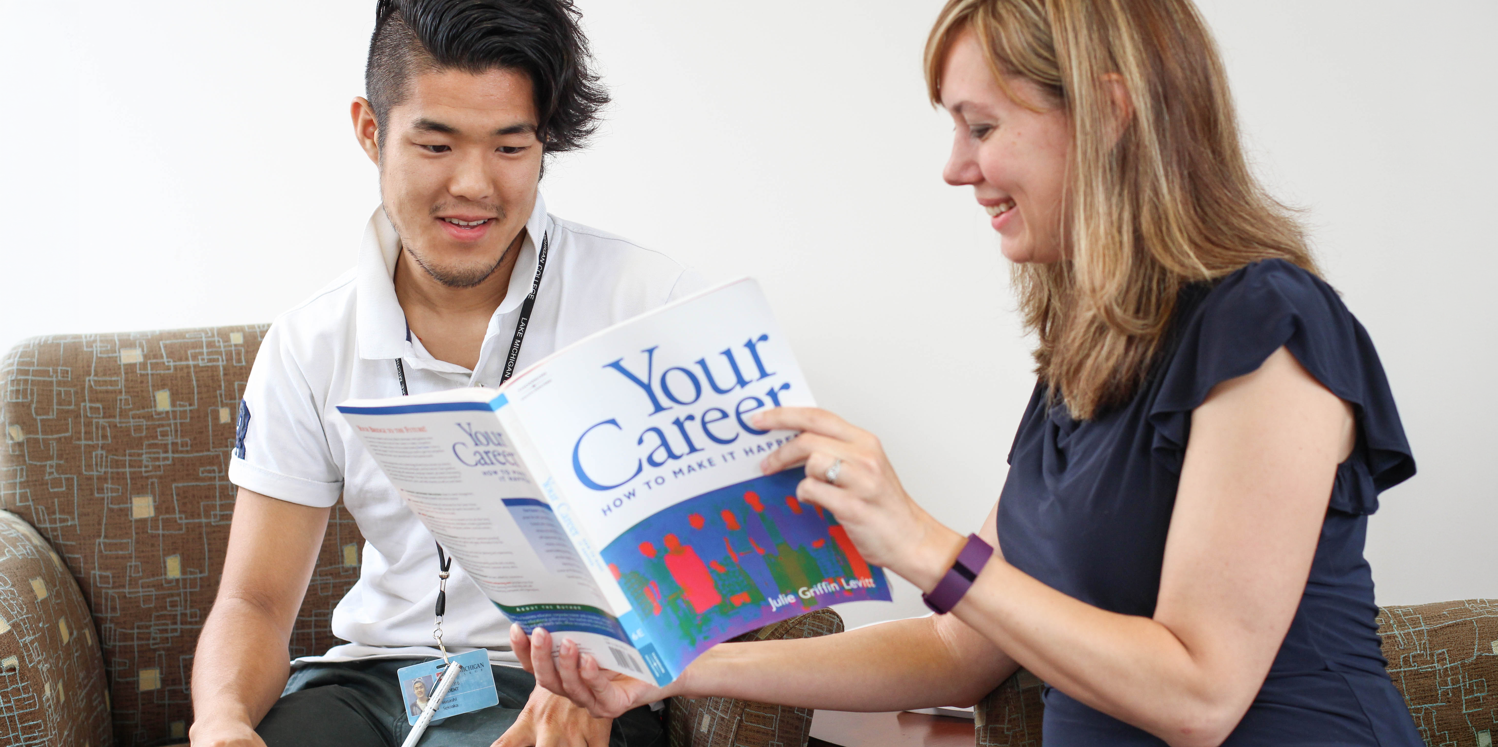 Two people sitting on a couch looking at a brochure.