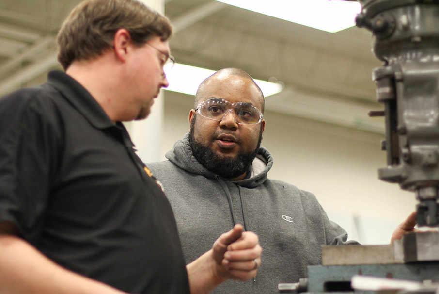 Non-traditional student and instructor working with machinery in the lab