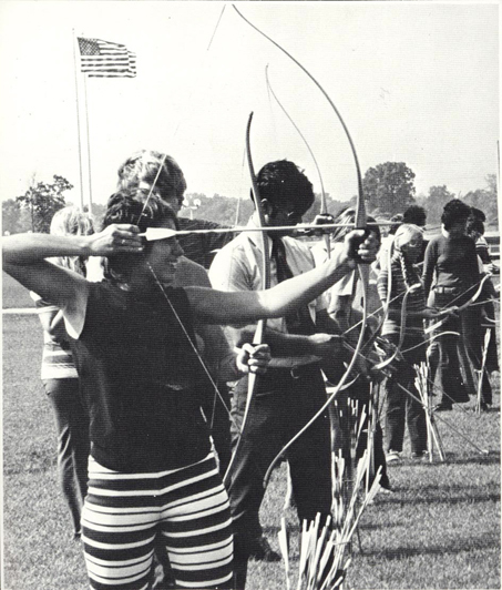 Students lined up with archery bows and arrows ready.