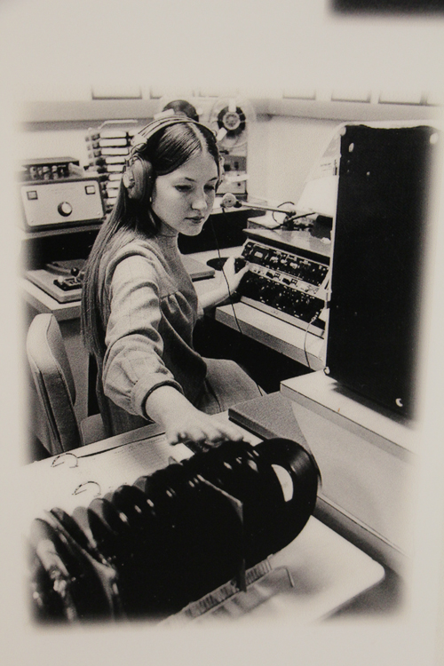 Woman working at a computer wearing headphones, maybe radio equipment.
