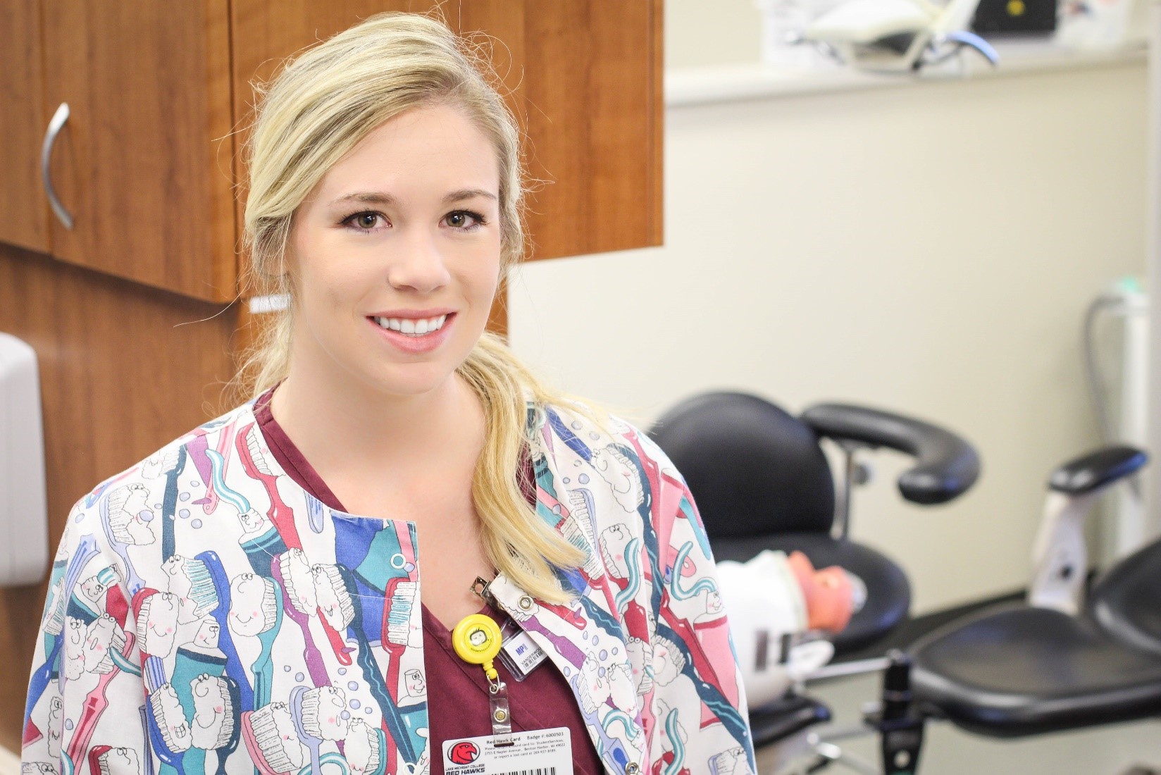 A student in tooth-themed scrubs smiles at the camera.