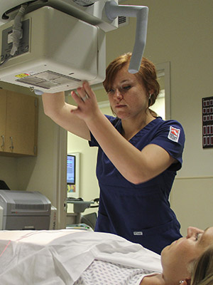 Student uses x-ray equipment to scan a volunteer.