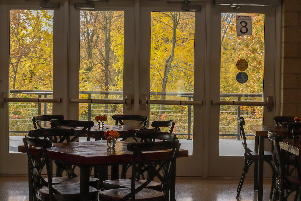 Interior of the tasting room with a cozy table in the foreground and a door to a bright exterior deck in the background.