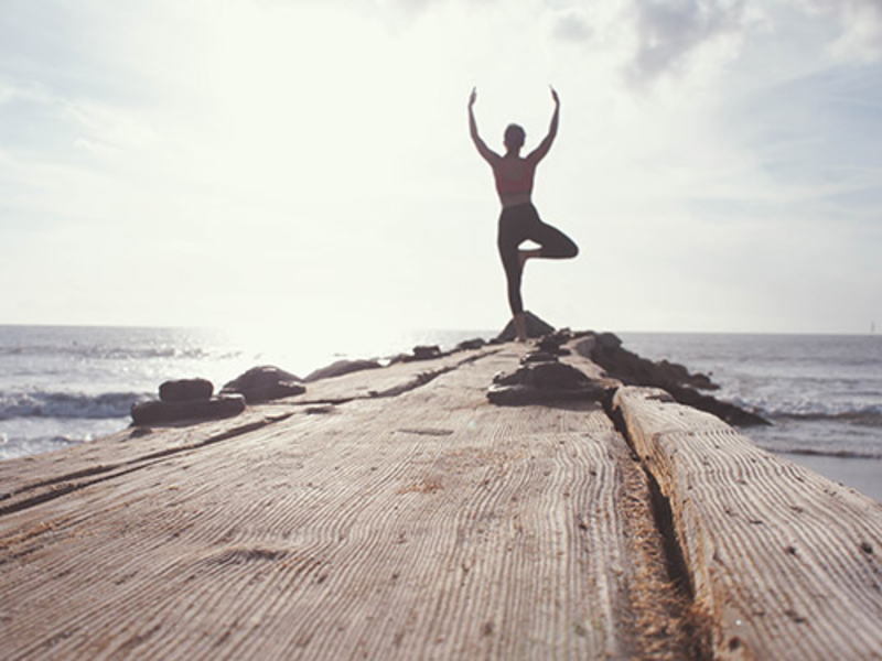 Man doing a yoga pose near water