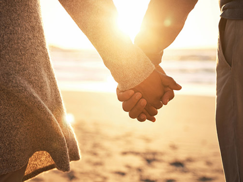 Couple holding hands at the beach at sunset