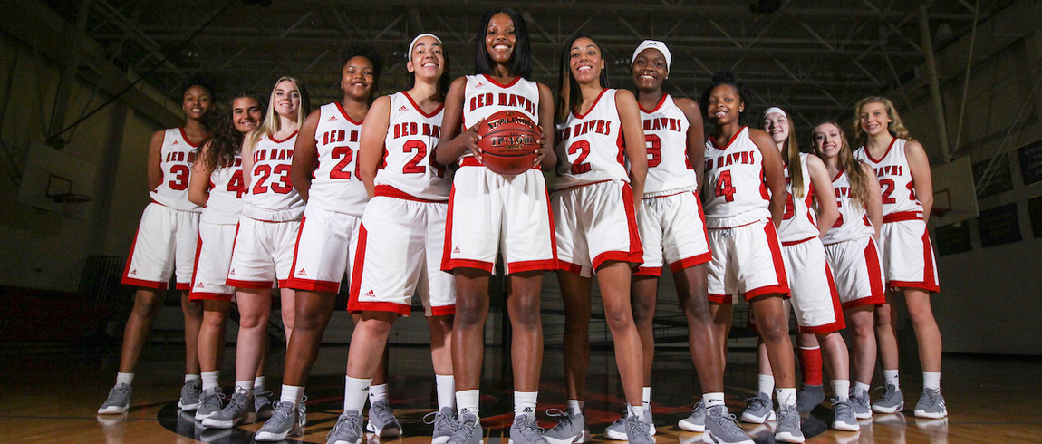 women's basketball team posing in the LMC gymnasium