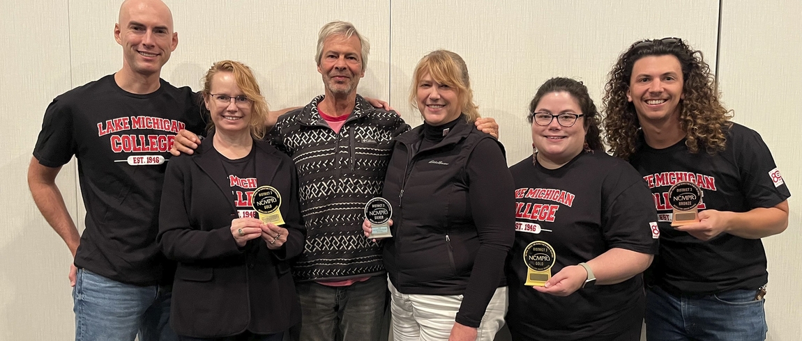 Group photo of individuals in Lake Michigan College attire holding medallions.