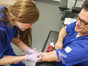 Phlebotomy students practice on each other