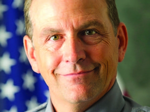 Headshot of Andrew Bauer, in uniform, in front of an American flag.