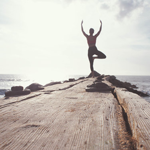 Man doing a yoga pose near water